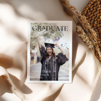 Modern, magazine-style graduation announcement template featuring a full-page photo of the graduate with elegant serif typography. The minimalist design highlights the graduate’s name, university, and class year in a clean, sophisticated layout. The announcement is displayed on soft beige fabric with natural woven and dried floral accents, creating a warm and stylish presentation. Ideal for high school or college graduates.
